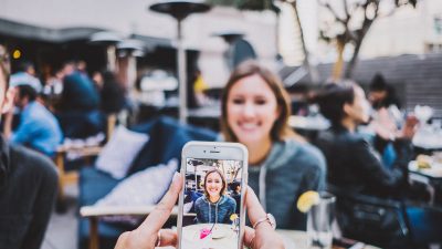 Eine Frau wird in einem Restaurant mit einem Smartphone fotografiert.
