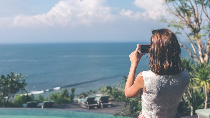 Eine Frau fotografiert mit ihrem Smartphone das Meer