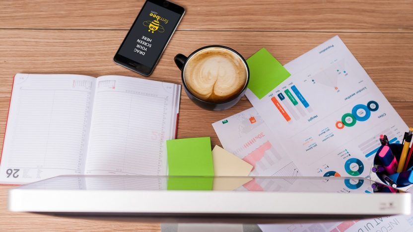Smartphone, Terminkalender, Kaffee, Post-Its: Für eine Kommunikationsstrategie liegen diese Dinge auf eine Schreibtisch.