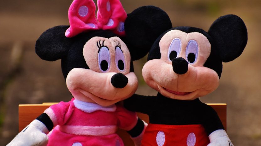 Mickey Mouse und Minie Mouse umarmen sich auf einer Parkbank.