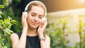Frau mit Kopfhörer freut sich und hört dabei einen Podcast